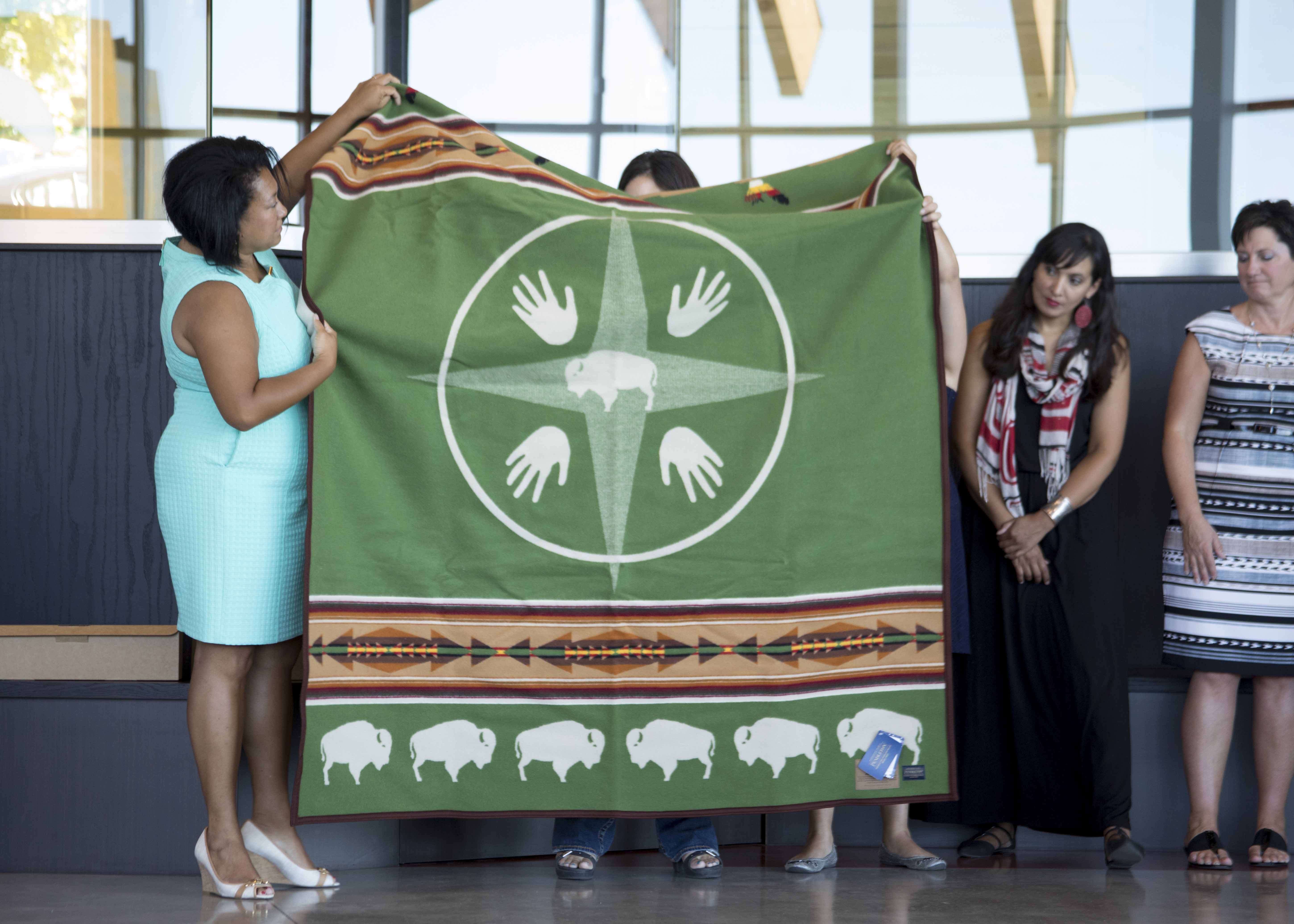 Paula Groves-Price holding a green Pendleton blanket with bison motif.
