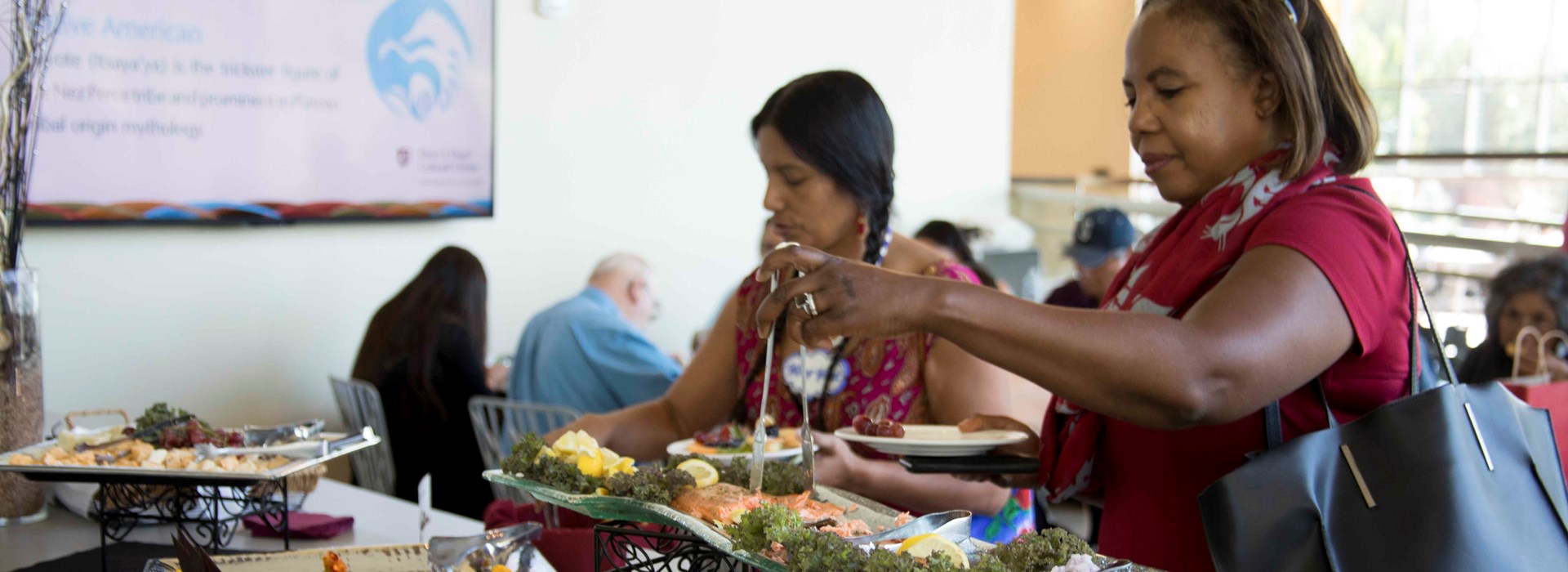 People plating food from the demo kitchen buffet.